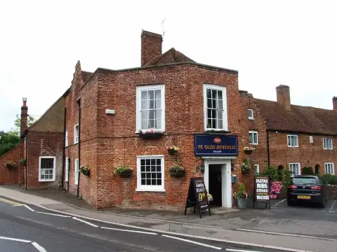 Red-brick corner pub with sash windows, a blue name board and a tiled roof behind
