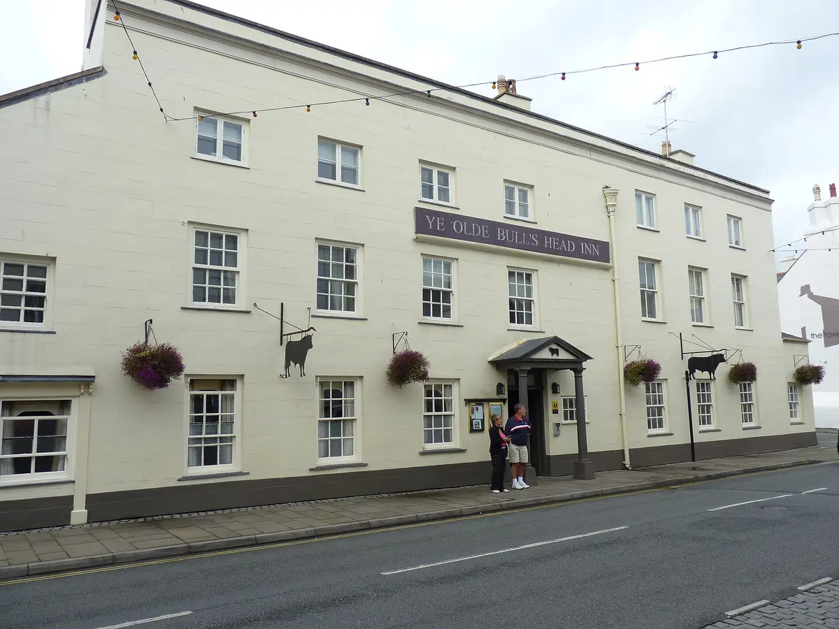 Long cream Georgian inn front with a purple name board and two black cut-metal bull signs