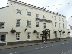 Long cream Georgian inn front with a purple name board and two black cut-metal bull signs