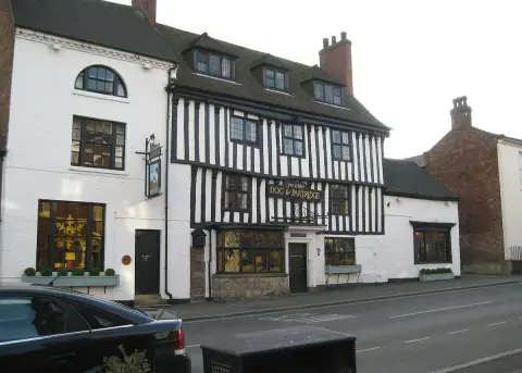 Timber-framed inn with three dormers and a leaded bay window, hanging sign and a Union flag