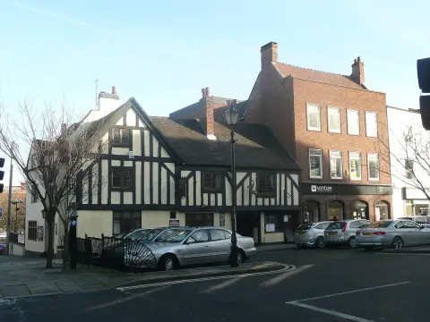 The pub seen across a road junction in winter sun, brick offices rising behind it