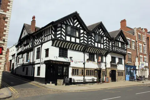 Three-gabled black-and-white timber-framed inn on a corner, board reading Built 1622