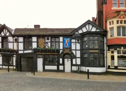 The same timbered pub from across the cobbles, its bay window lettered Rebuilt 1636