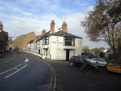 White pub on a street corner in low autumn sun, name lettered across the gable end