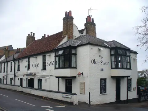 White rendered riverside pub with black bay windows, the name painted large across the wall