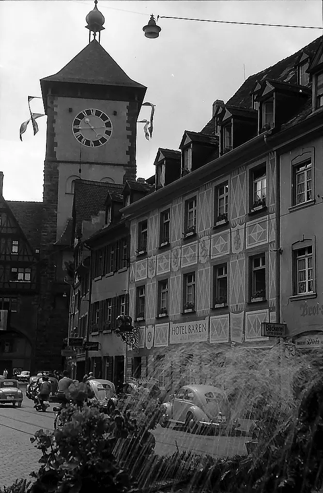 The painted front of the Hotel Bären beside the Schwabentor clock tower in 1957, with cars of the period in the street