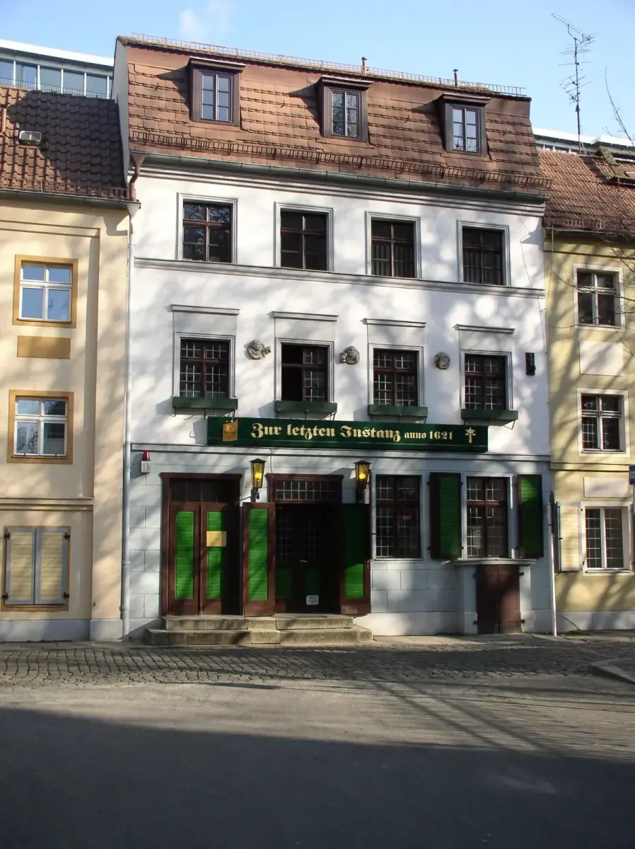 White house with green shutters and a green sign reading Zur letzten Instanz anno 1621