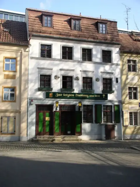 White house with green shutters and a green sign reading Zur letzten Instanz anno 1621